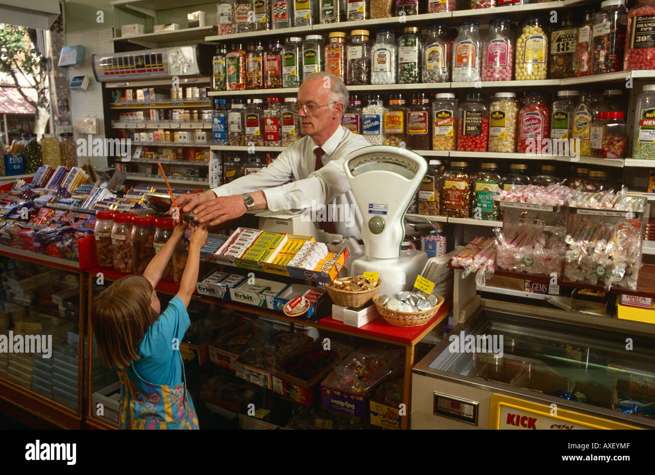 Una pasticceria proprietario del negozio con le mani su un pacchetto di caramelle di una giovane ragazza in Frinton Essex, Regno Unito Foto Stock