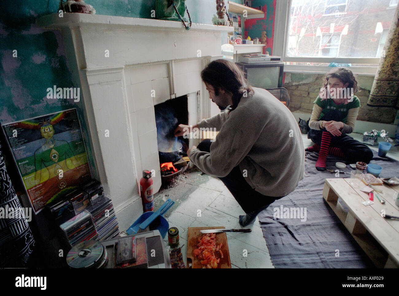 Giovane uomo cucinare un pasto nel caminetto a Kennington squat a sud di Londra. Foto Stock