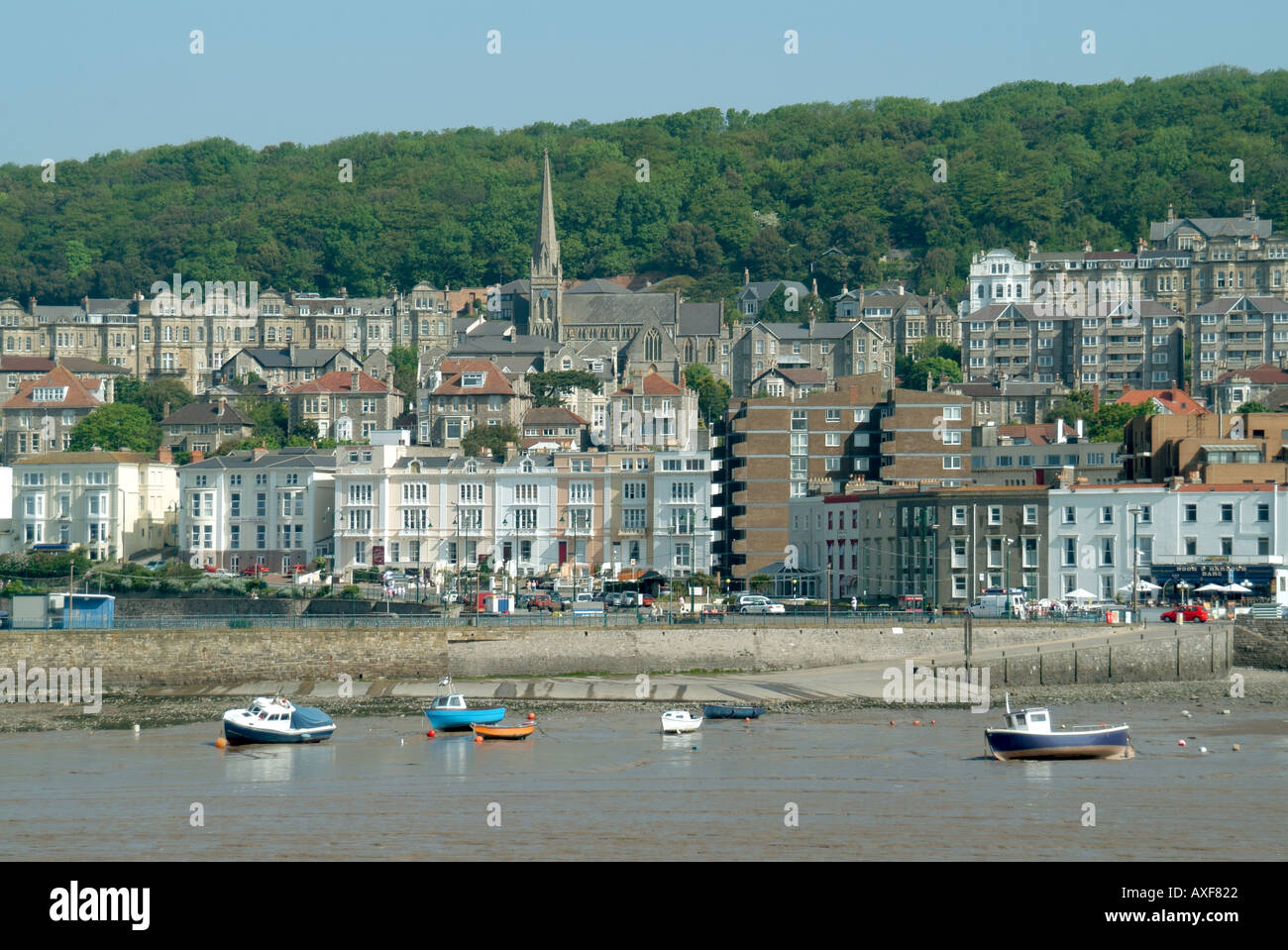 Weston Super Mare imbarcazioni ormeggi a bassa marea con edifici sul lungomare e la guglia della chiesa su una collina al di là Foto Stock