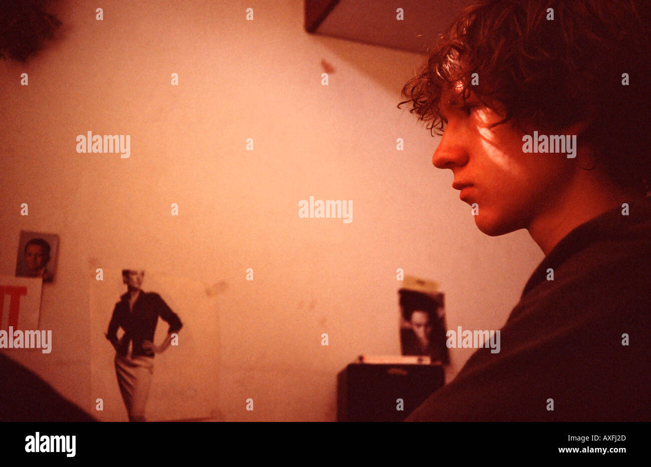 Piana interna della parete della camera poster poster boy 15 20 capelli ricci breve sedersi faccia tristezza arrabbiato depressione luce sun sunbeam port Foto Stock