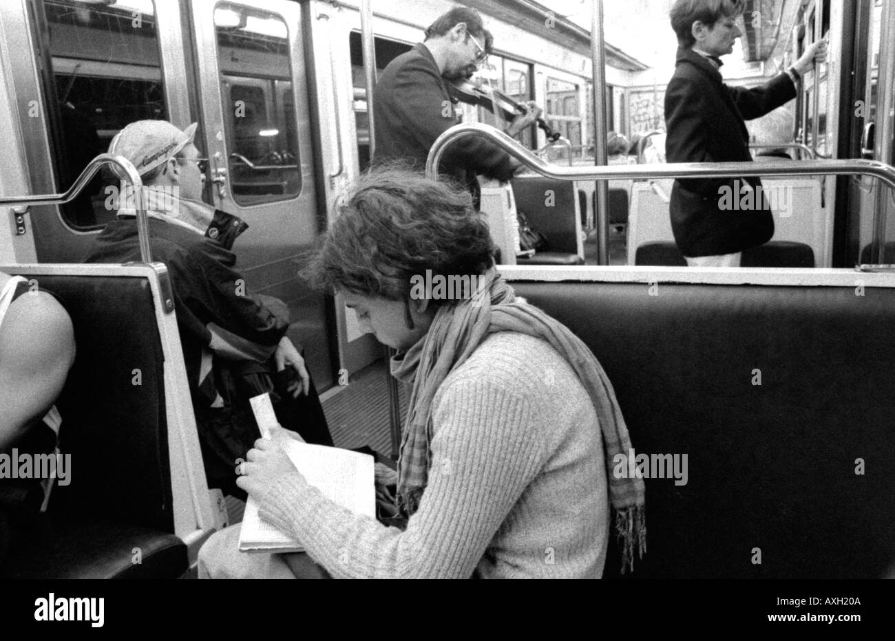 Lettura della ragazza sulla metropolitana di Parigi il violinista in background Foto Stock