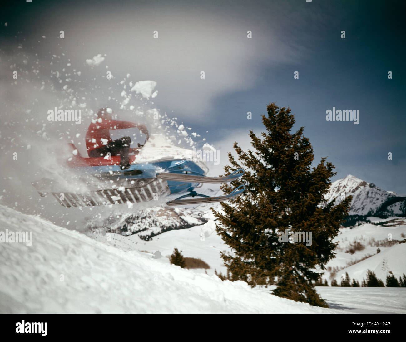 Audace crash snowmobiler off una cresta nevosa e prende all'aria in un emozionante giro di inverno Foto Stock