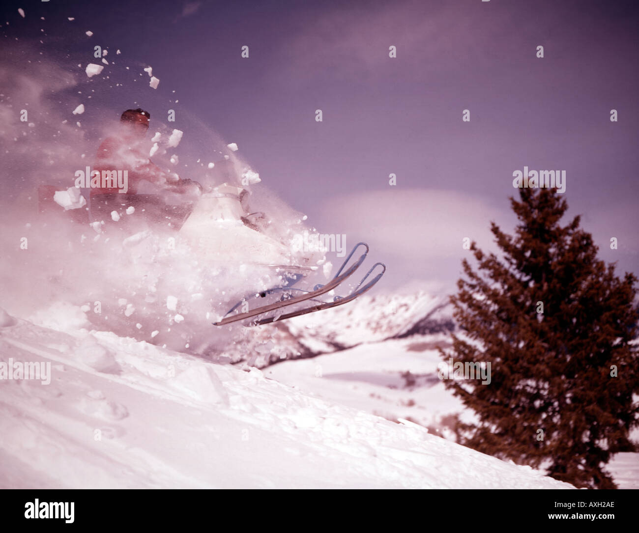 Audace crash snowmobiler off una cresta nevosa e prende all'aria in un emozionante giro di inverno Foto Stock