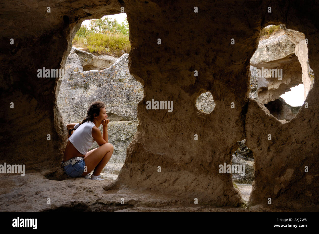 Donna seduta turistico in grotta tagliato nella roccia Foto Stock
