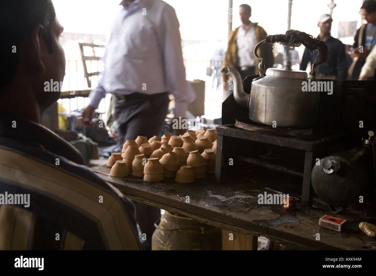 Un uomo corre un semplice tè in stallo il BBD Bagh area di Kolkata. Egli bolle tè in una stufa di kerosene e serve chai in pentole di creta Foto Stock