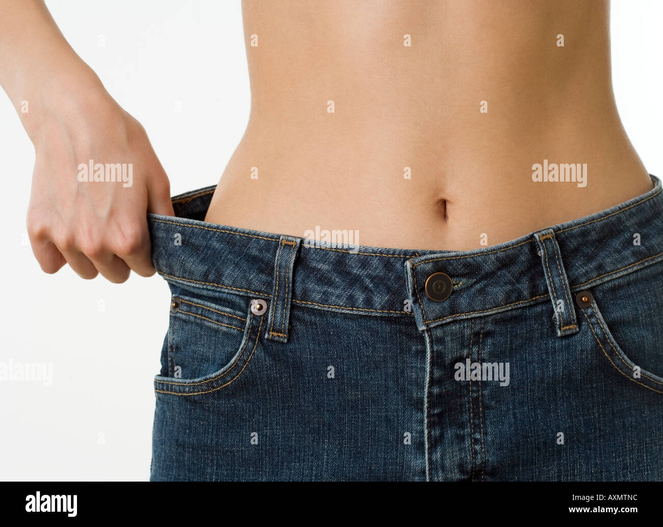 Close up della donna tenendo alla cintura dei pantaloni lontano dall'anca Foto Stock