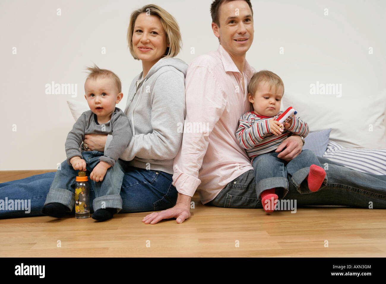 Il padre e la madre seduta di schiena, figli sui giri Foto Stock