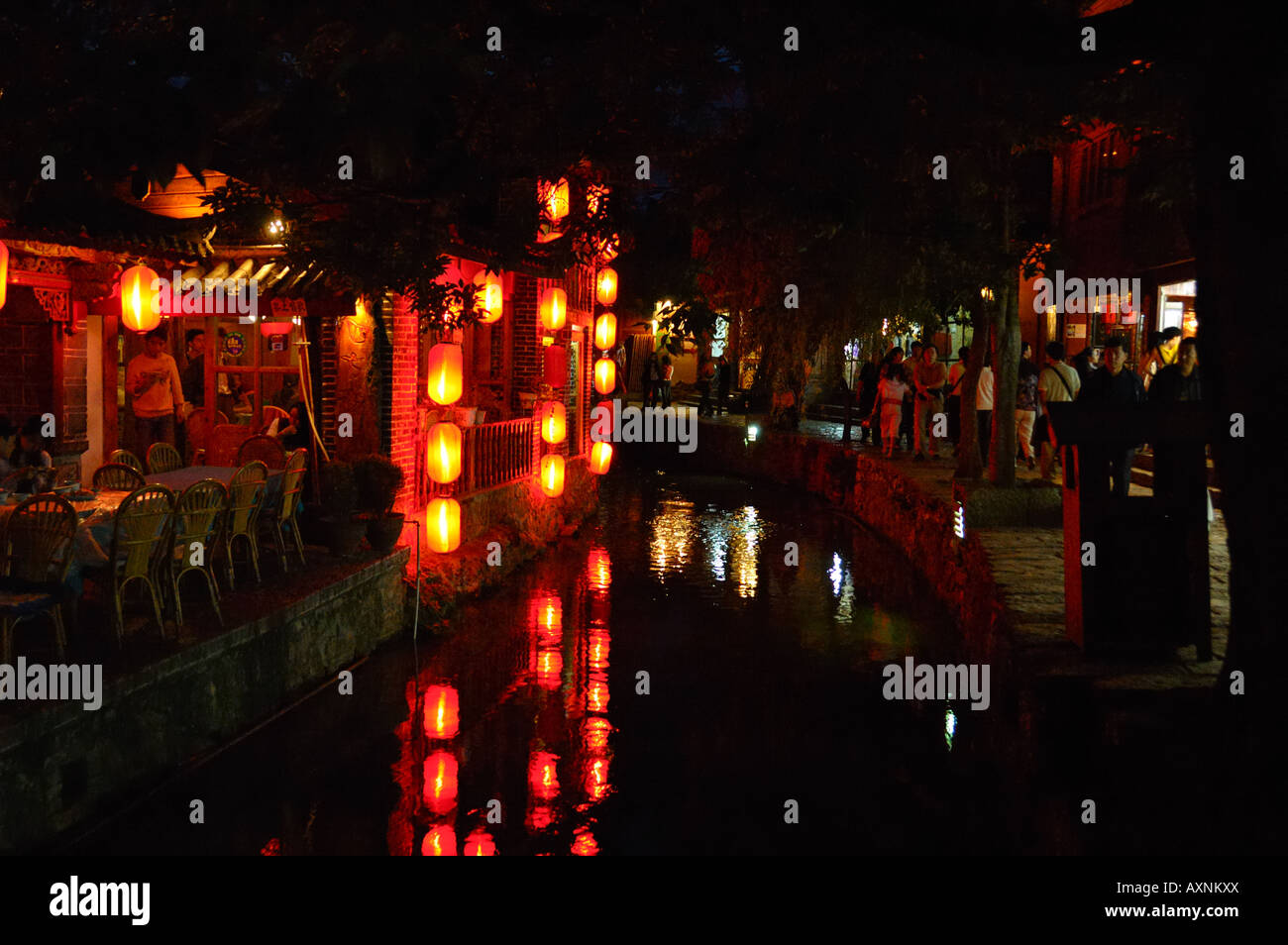 Lijiang di notte. Lanterne rosse decorare i negozi lungo la strada e riflettere sull'esecuzione creek. Lijiang, Yunnan in Cina. Foto Stock