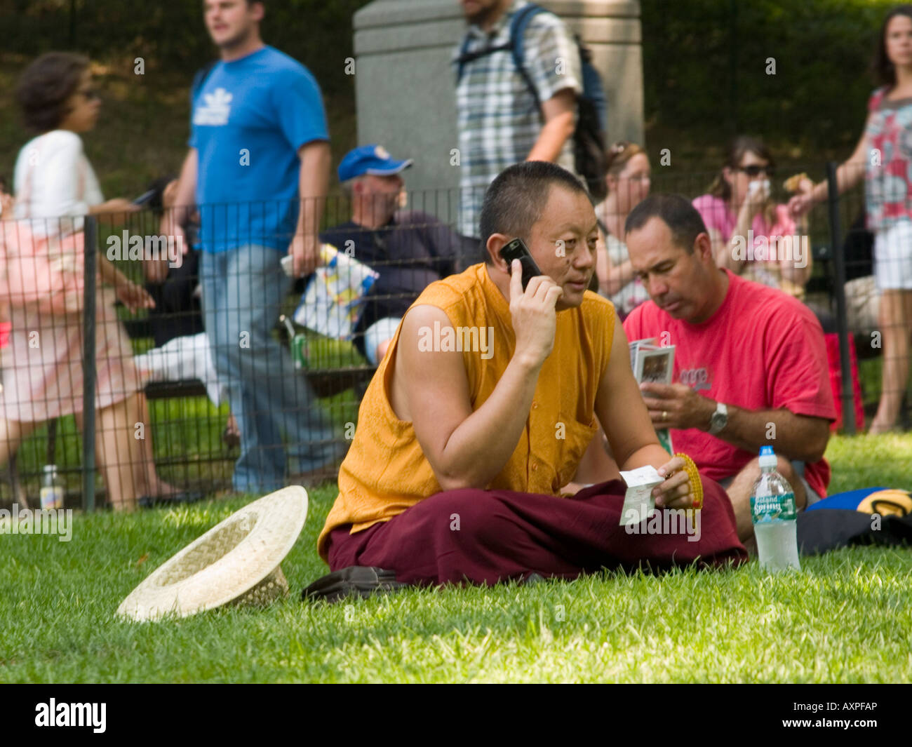 Un giovane uomo di colloqui sul suo telefono cellulare come egli si siede sul prato di Central Park di New York City STATI UNITI D'AMERICA Foto Stock