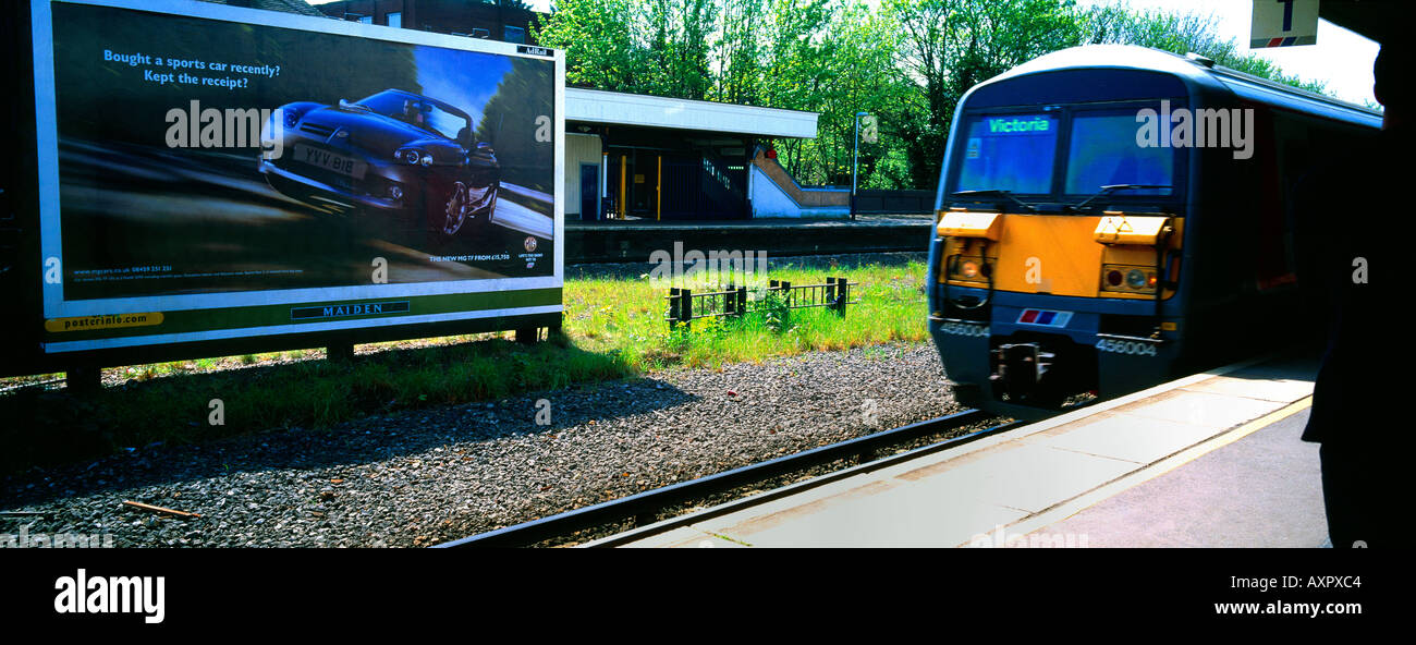 Cheam Stazione ferroviaria Treno in avvicinamento piattaforma Auto tabellone pubblicitario Foto Stock