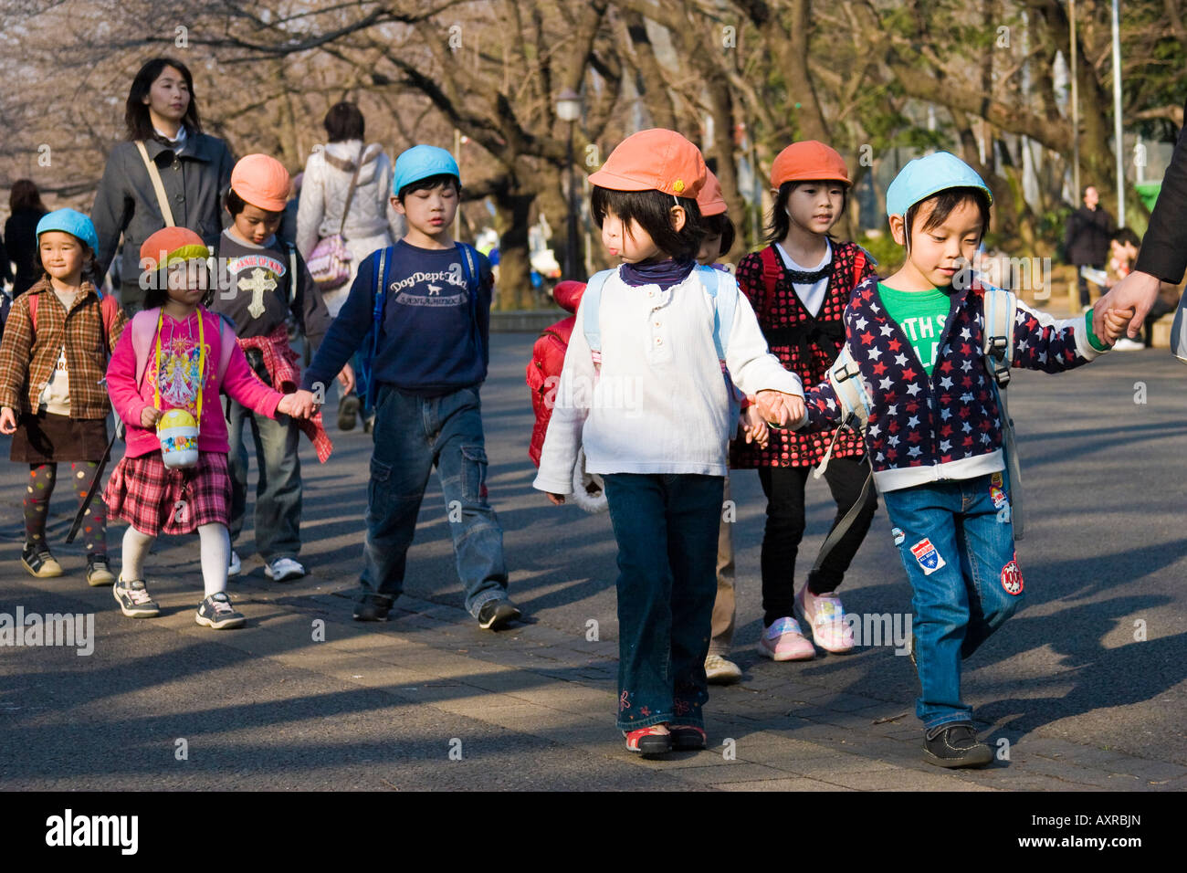 Un giovane giapponese la scuola dei bambini a camminare in una linea tenendo le mani nel Parco di Ueno Tokyo Giappone Foto Stock
