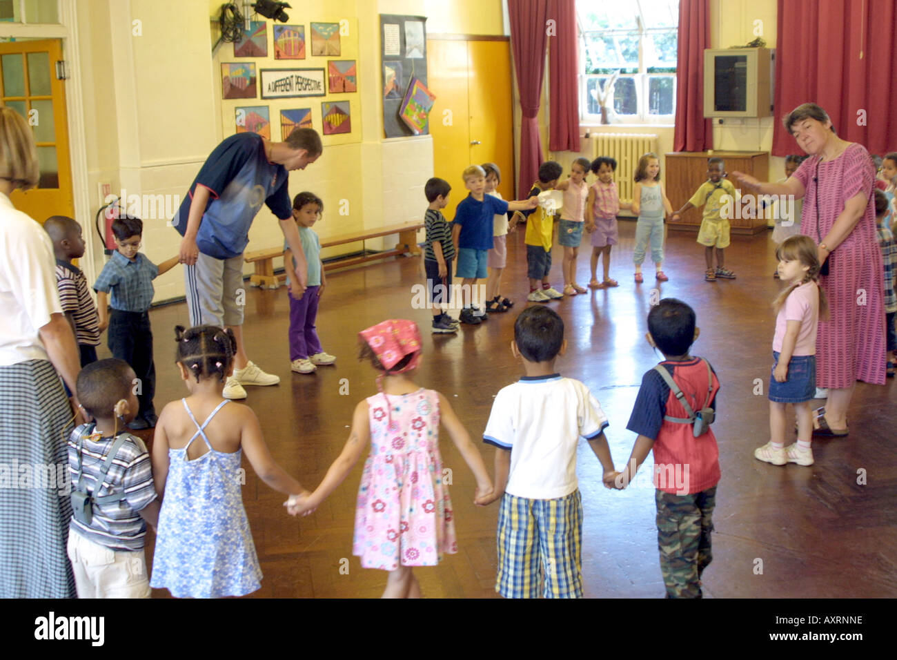 Bambini della scuola materna in piedi in cerchio tenendo le mani in palestra Foto Stock