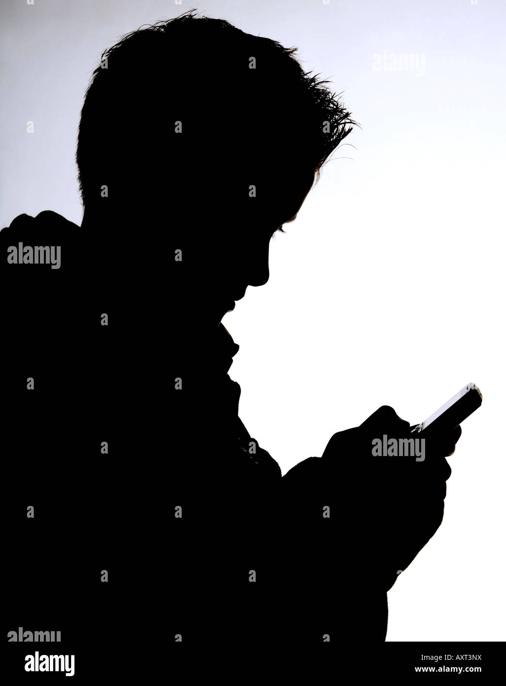 Una silhouette di un ragazzo adolescente scrivere messaggi con il telefono cellulare. Foto da Jim Holden. Foto Stock