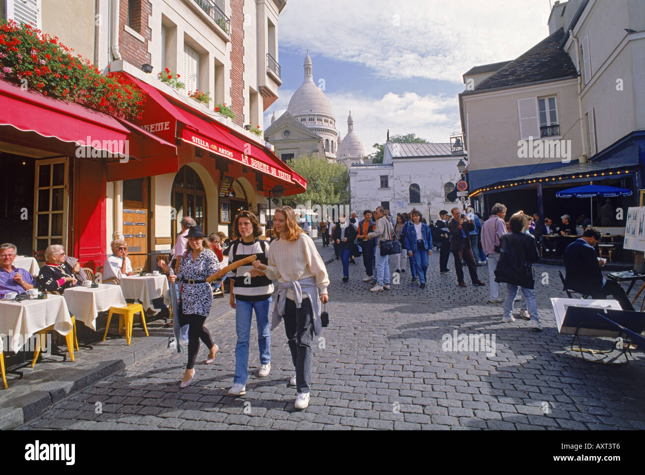Caffè, negozi e turisti a Place du Tertre con il Sacro Cuore a Montmartre a Parigi Foto Stock
