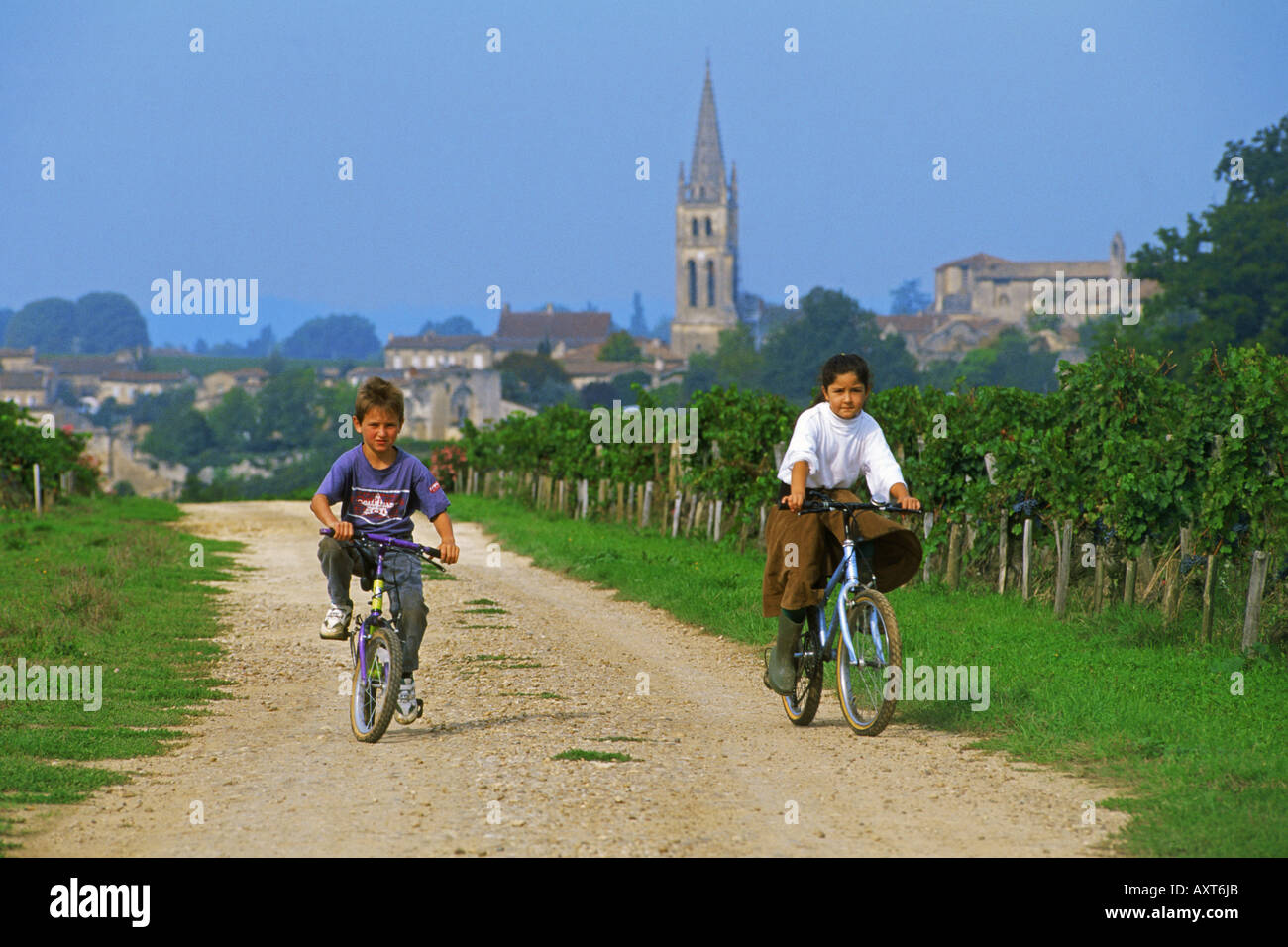 Due bambini della scuola di equitazione biciclette attraverso vigneti di Bordeaux vicino al villaggio di St Emilion in Francia Foto Stock