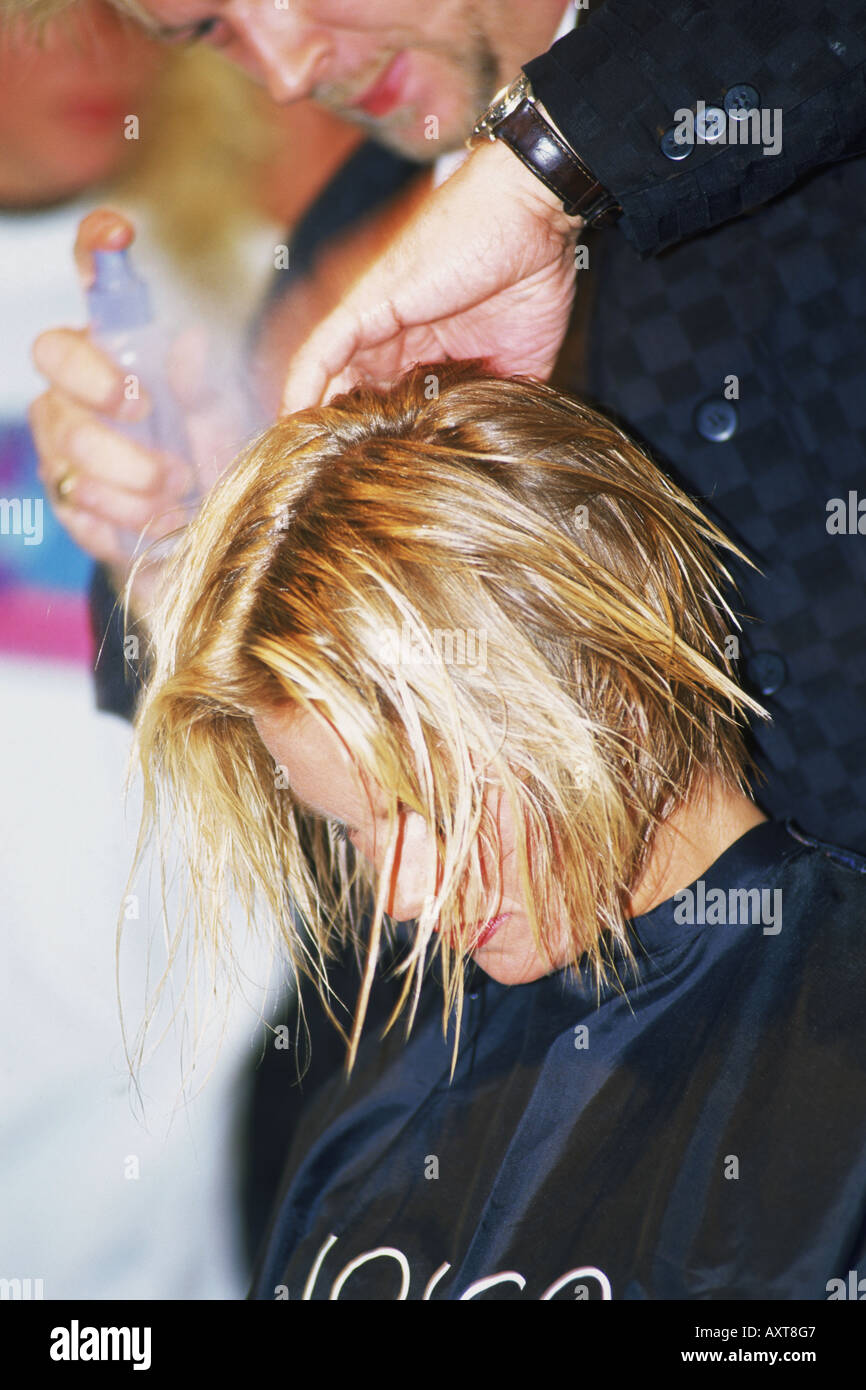 Donna getting taglio capelli, shampoo e perm da estetista a parrucchiere Foto Stock