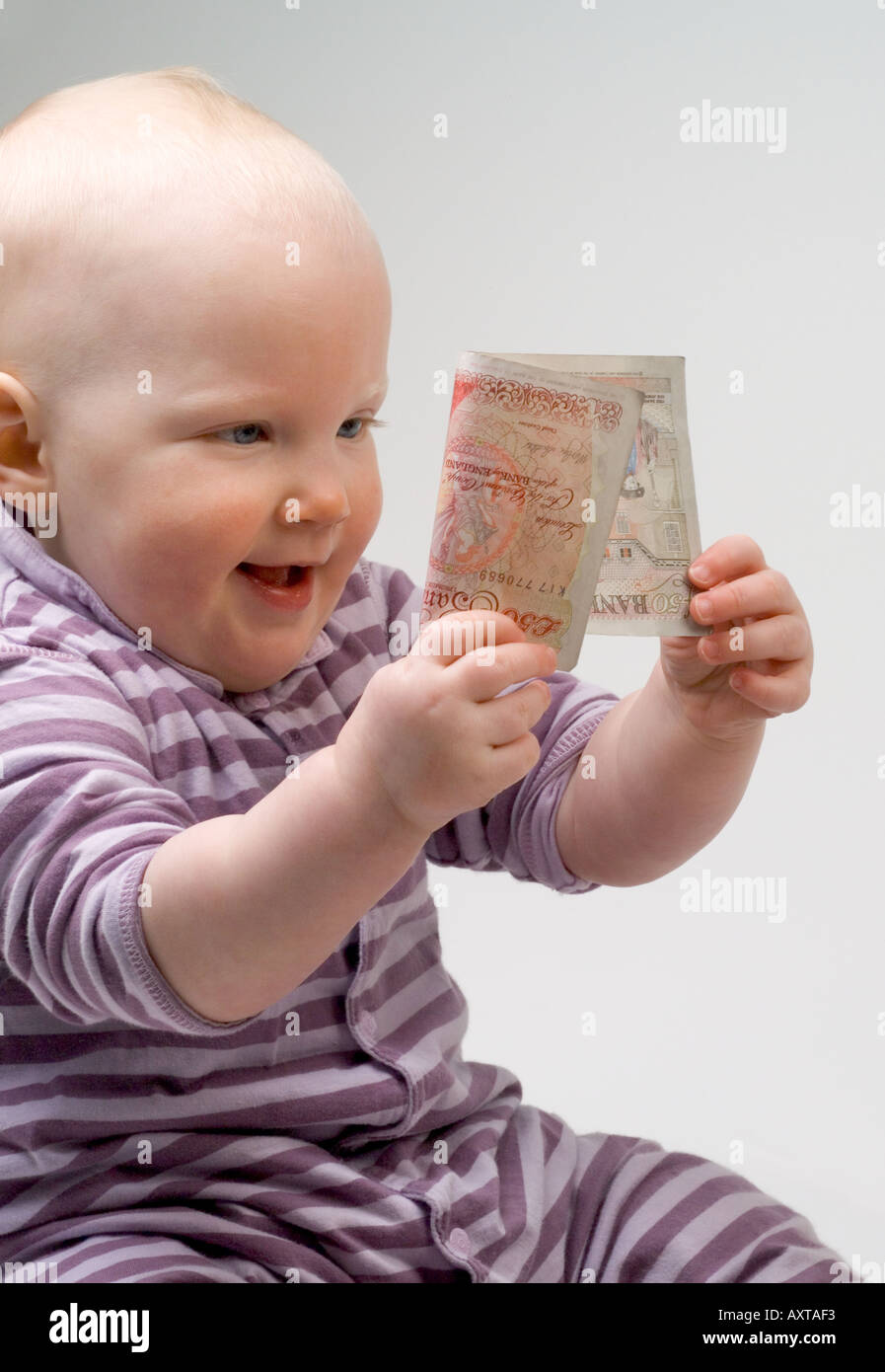 Bambino di undici mesi tenendo 50 cinquanta pound note Foto Stock