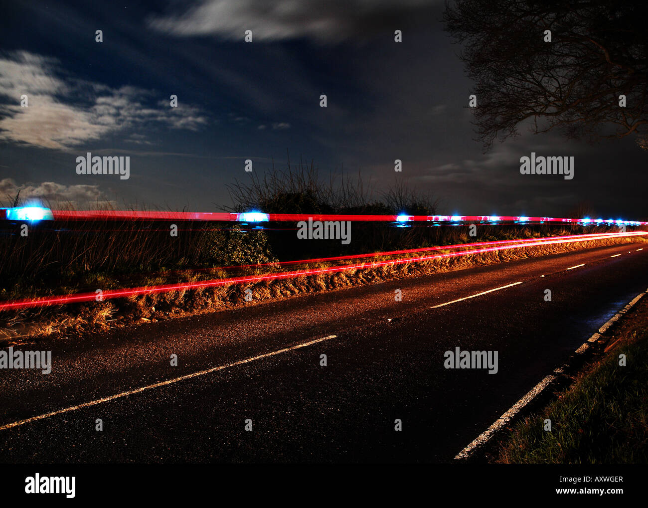 Chiamata di emergenza - un auto della polizia di luci lampeggianti sentiero sulla strada di un paese di notte Foto Stock