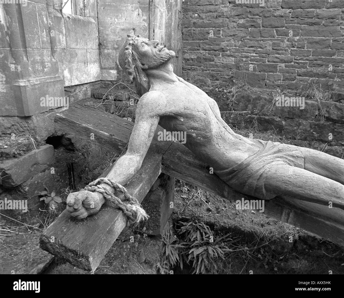 Immagine in bianco e nero della statua di Gesù su una croce di legno abbandonata nelle rovine della Brougham Hall in Cumbria Foto Stock