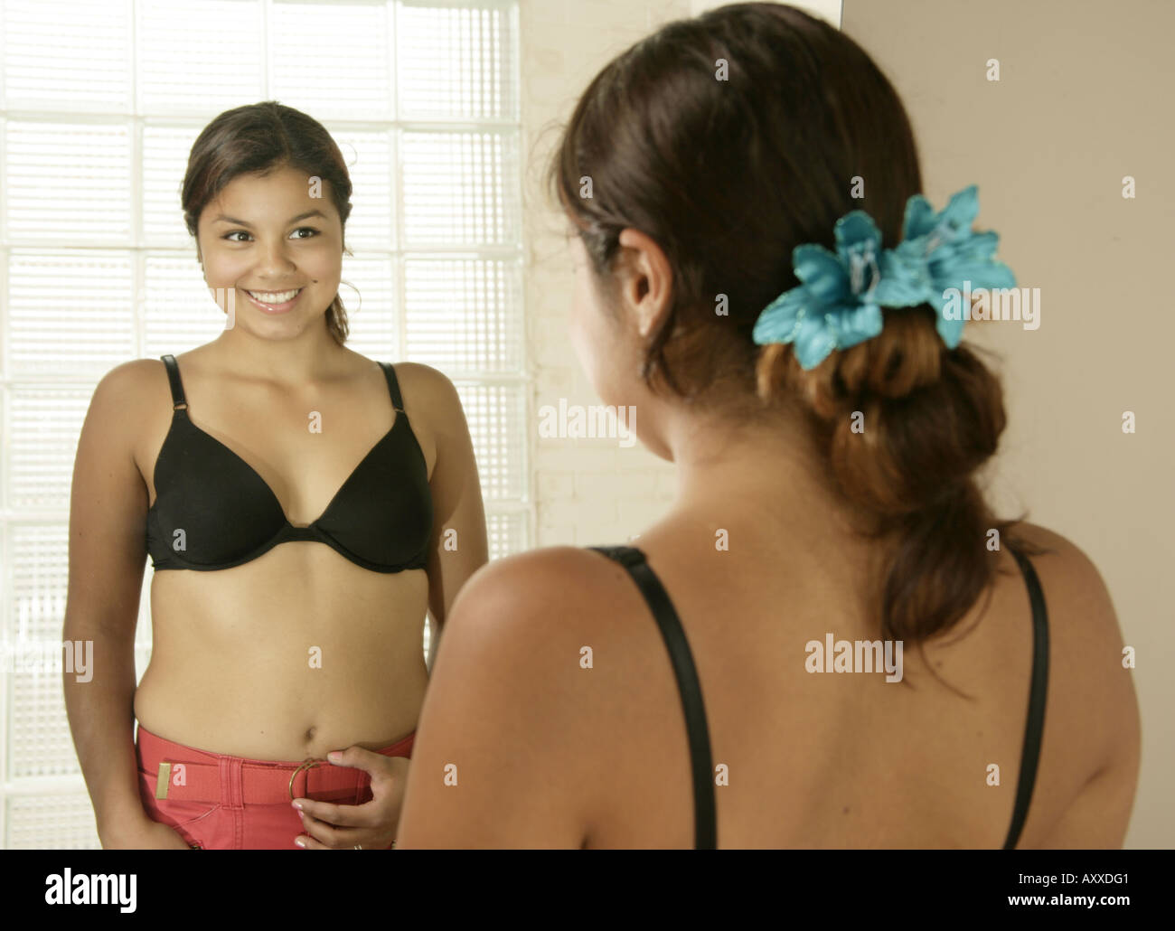 Giovane ragazza è felice con lei guarda come ella stessa controlli servendosi di uno specchio. Foto Stock