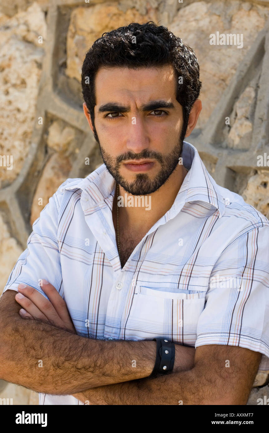 Giovane uomo arabo bracci ripiegati guardando la telecamera Foto Stock