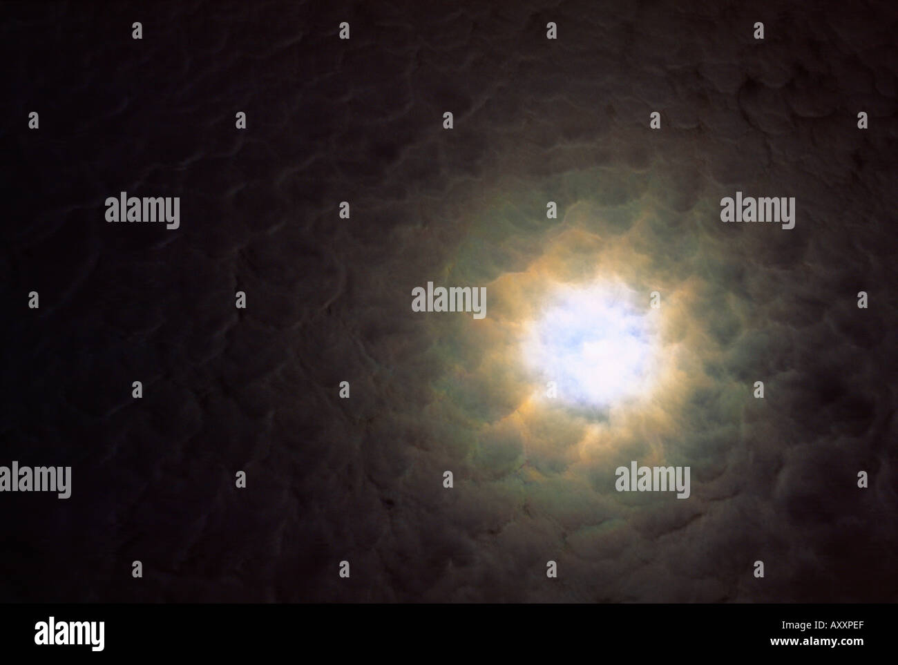Foro di luce attraverso la sottile copertura di cloud che mostra luna moonshine alo nel cielo notturno Foto Stock
