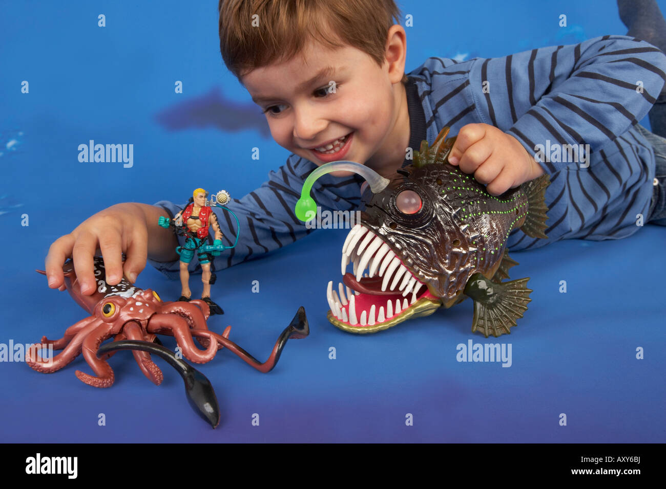 Un bambino gioca con sotto il mare action figure contro un sfondo oceano Foto Stock
