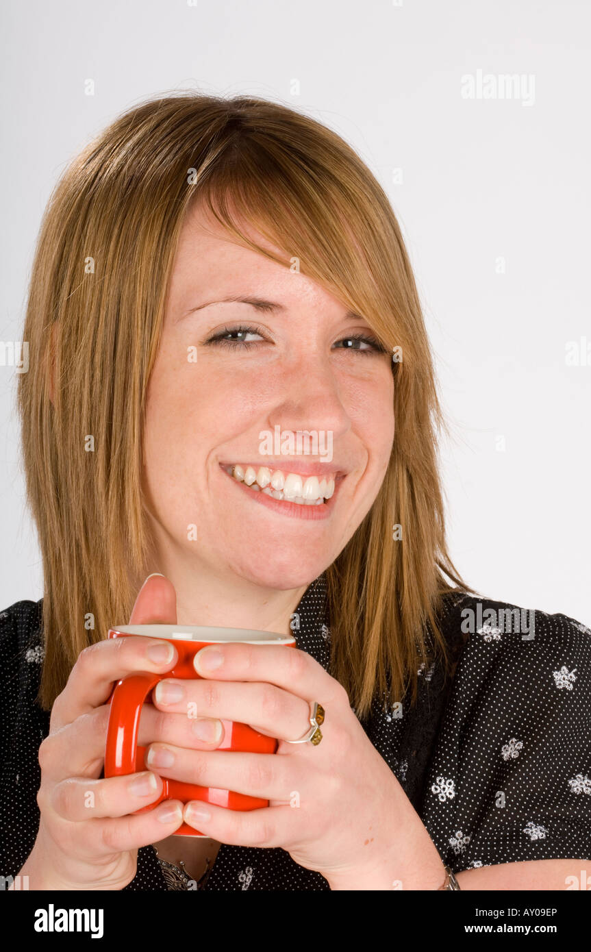 Una giovane donna ventenne tenendo un mug in entrambe le mani. Foto da Jim Holden. Foto Stock