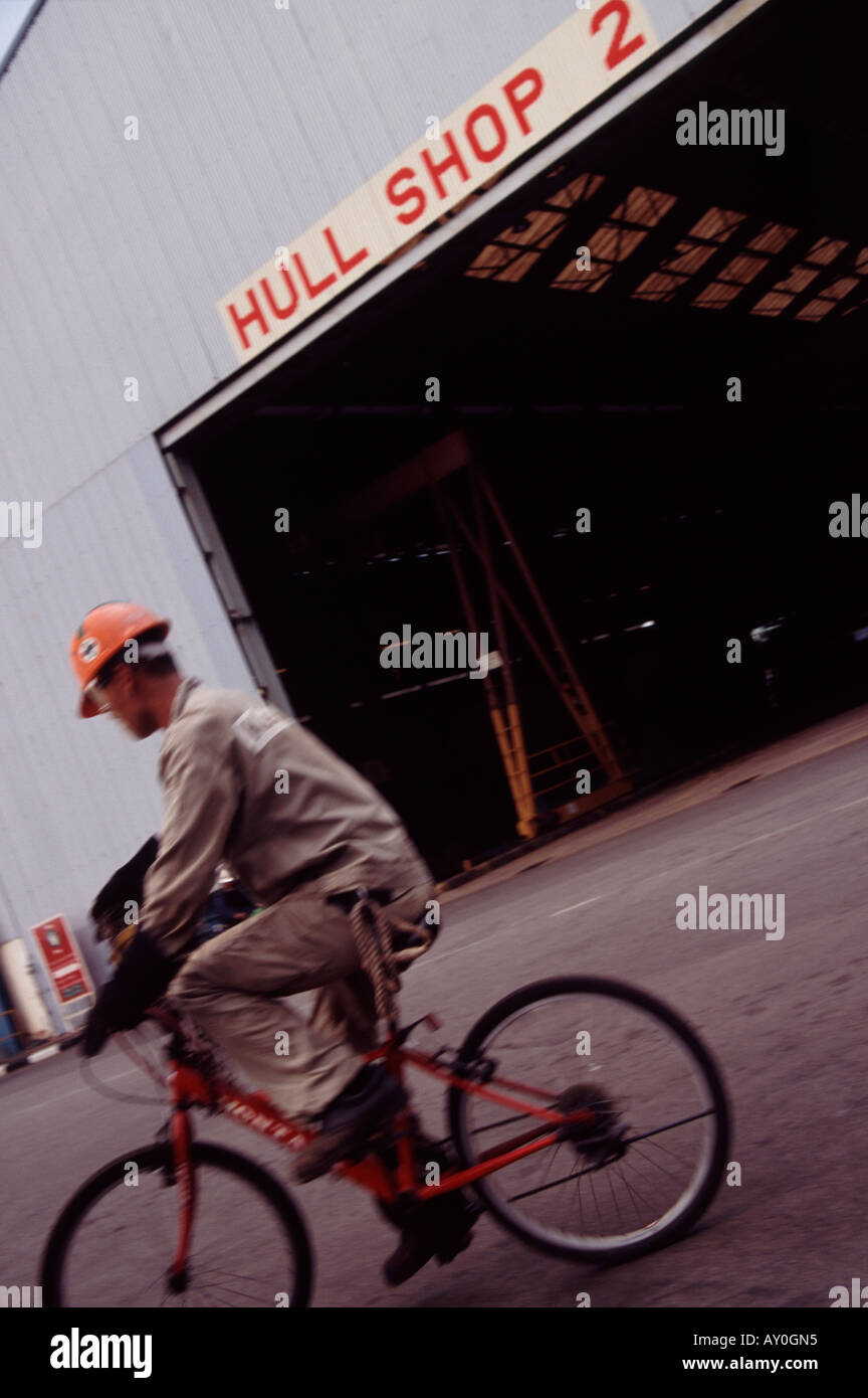 Shipworker sulla bicicletta pedalando attraverso il negozio dello scafo a keppel shipyard di Singapore fareast asia Foto Stock