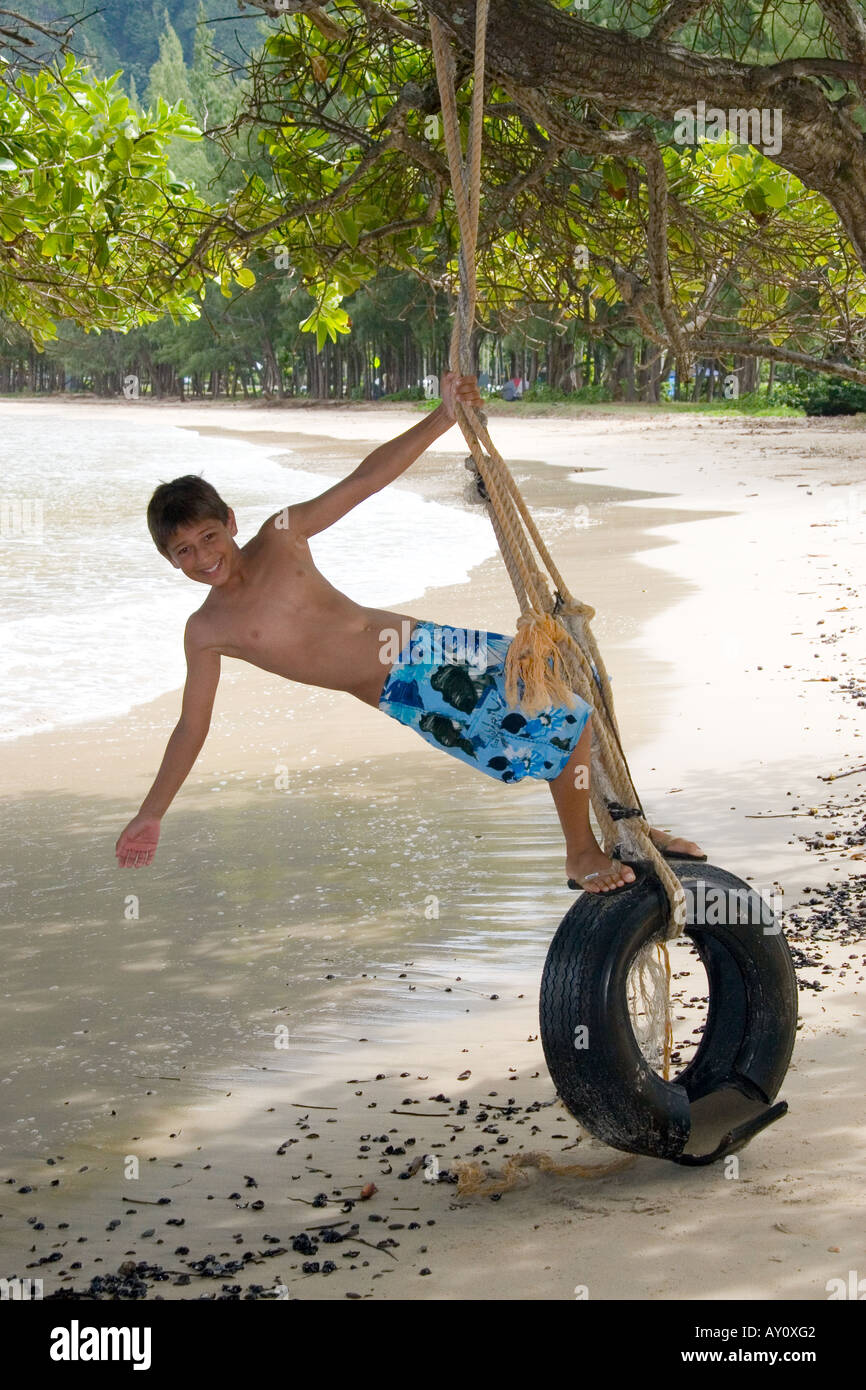 Ragazzo su un pneumatico swing sulla spiaggia in Oahu, Hawaii Foto Stock