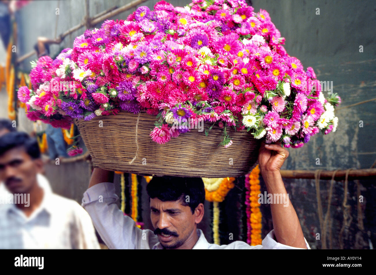 Un facchino che porta un cesto di vimini con un carico di fragrante a Dadar Flower Market il commercio all'ingrosso più grande mercato dei fiori a Mumbai. India Foto Stock