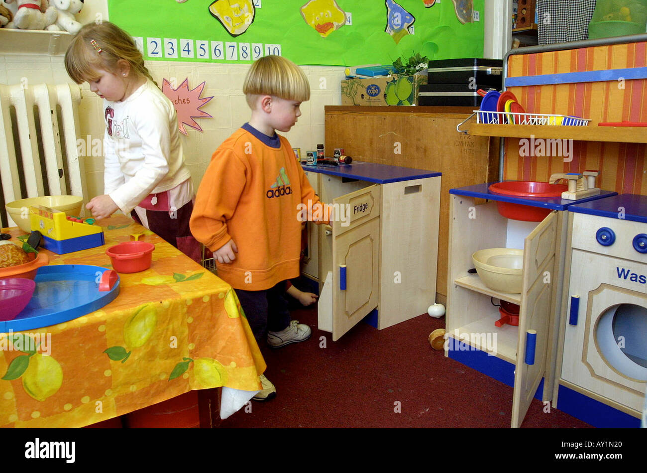 La scuola materna di classe home angolo con bambini che giocano in cucina Foto Stock