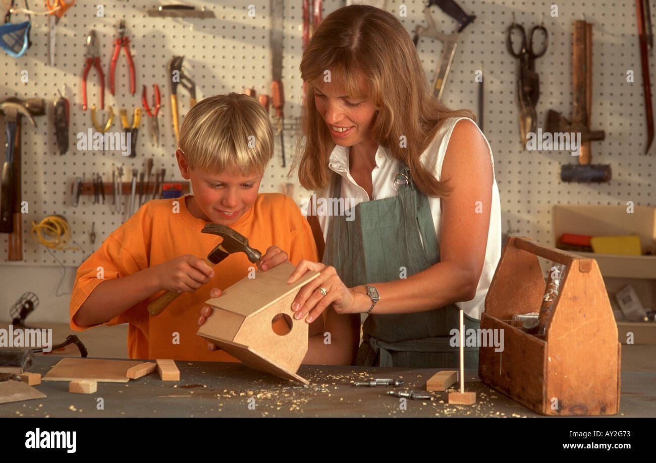 La madre del ragazzo aiuta a costruire birdhouse in officina Foto Stock