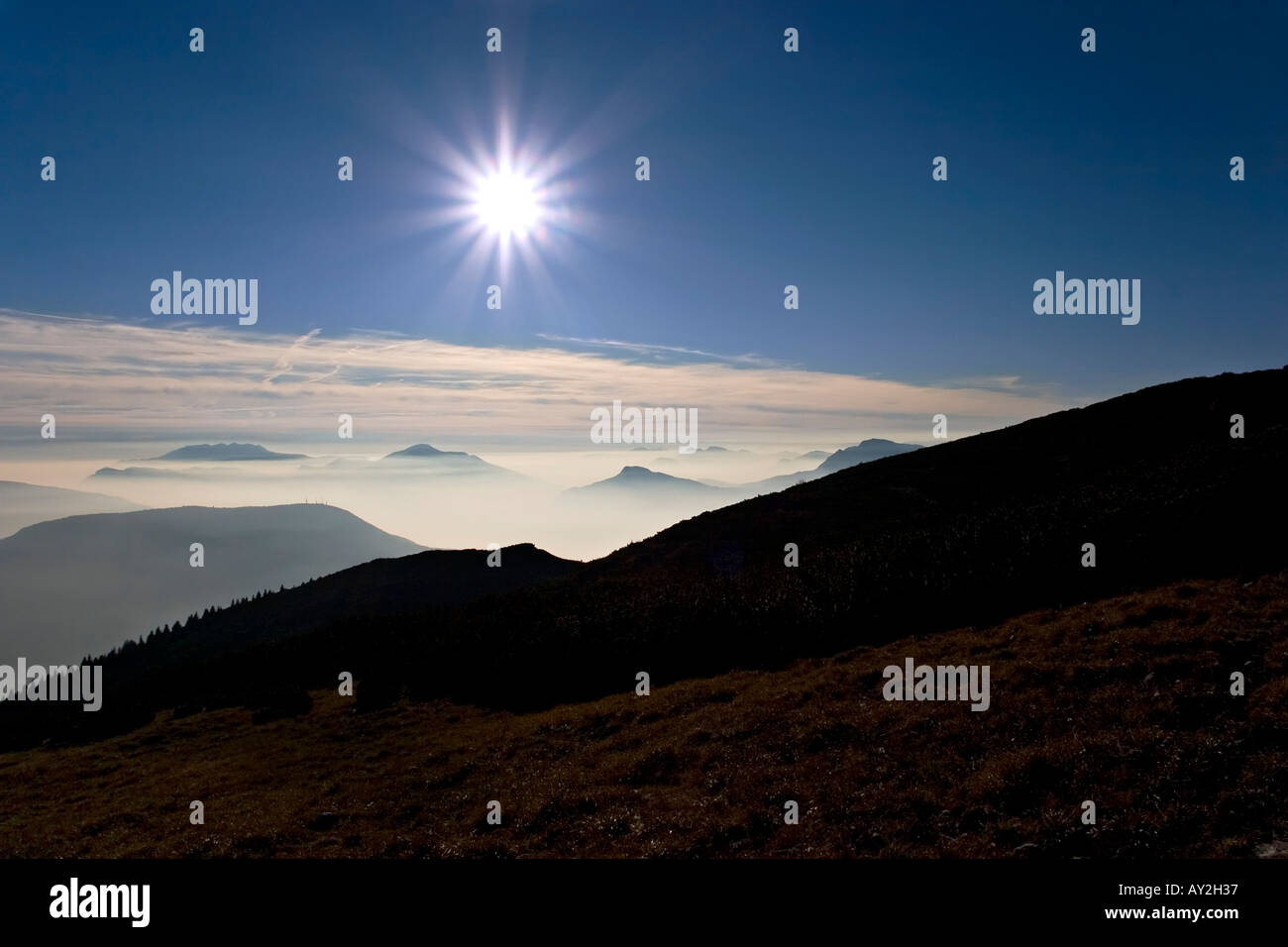 Panorama con montagne nuvole sole albero liscio e cielo blu Foto Stock
