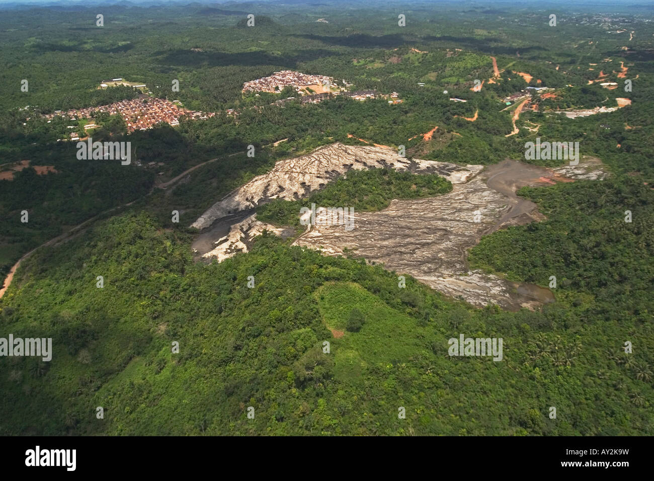 Vista aerea del commercial gold mine vecchia diga del recupero con guasto parete che mostra erosione di burrone e local township dietro, Ghana Foto Stock