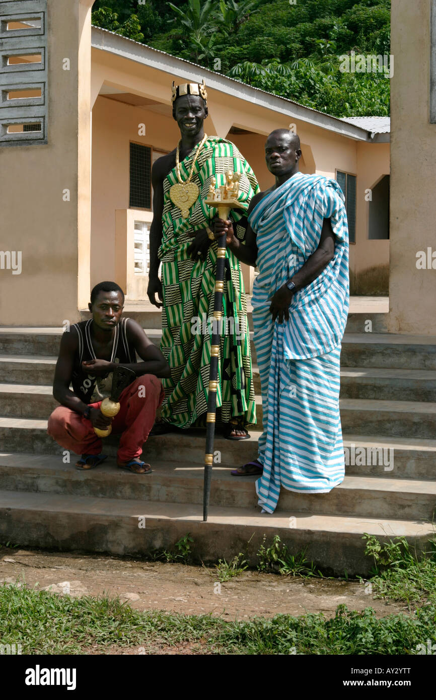 Capo villaggio in il tessuto Kente al di fuori del suo palazzo con la sua linguista azienda golden personale di ufficio e la sua spada bearer, Ghana Foto Stock