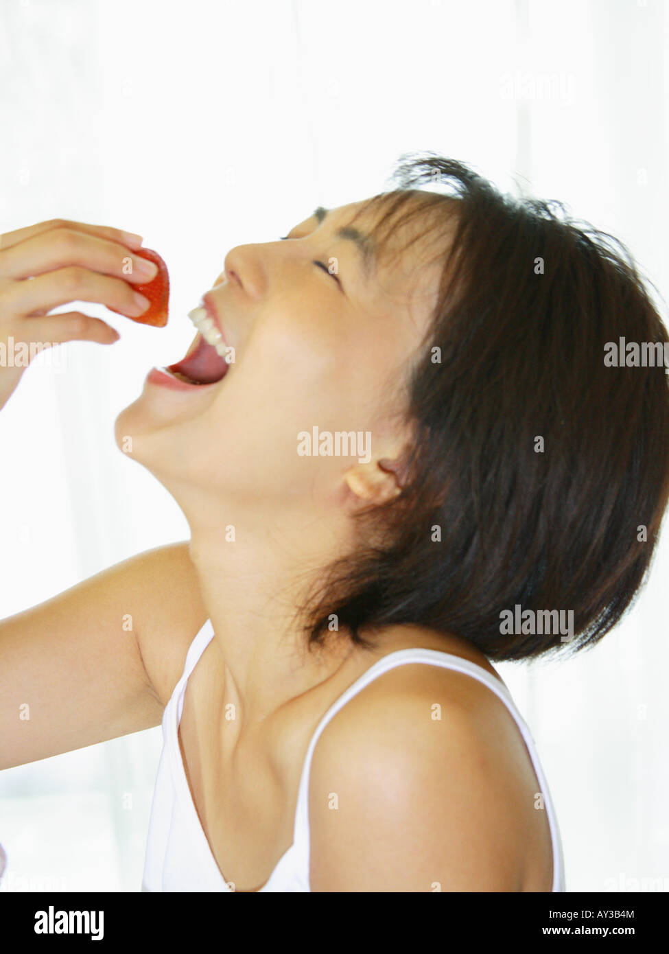 Close-up di una giovane donna di mangiare una fragola Foto Stock