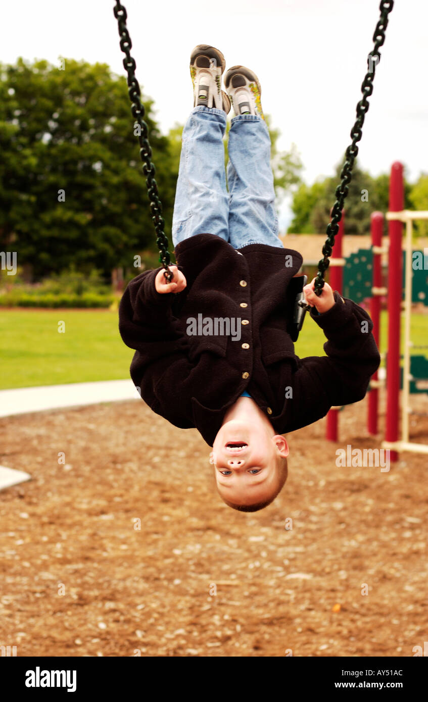 Cinque anni di vecchio ragazzo appeso a testa in giù su swing Foto Stock