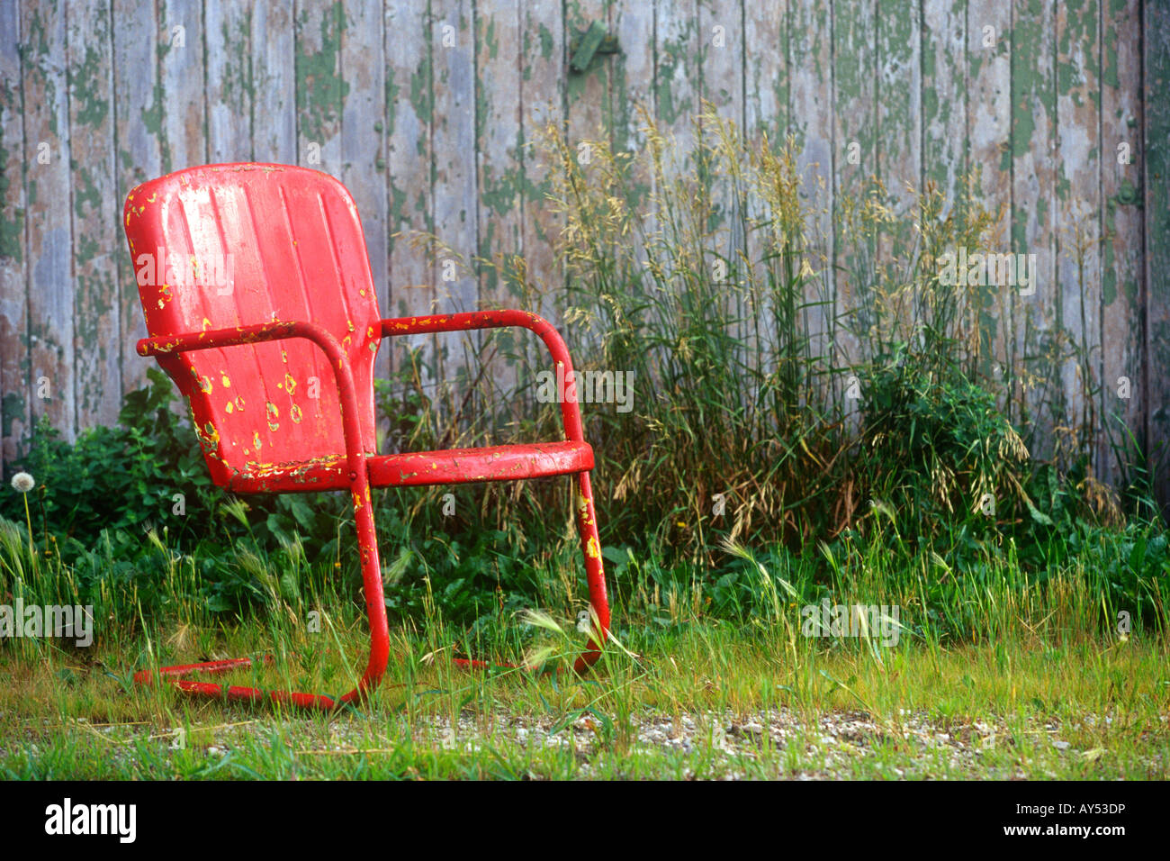 Una vecchia sedia rossa si appoggia all'aperto Foto Stock