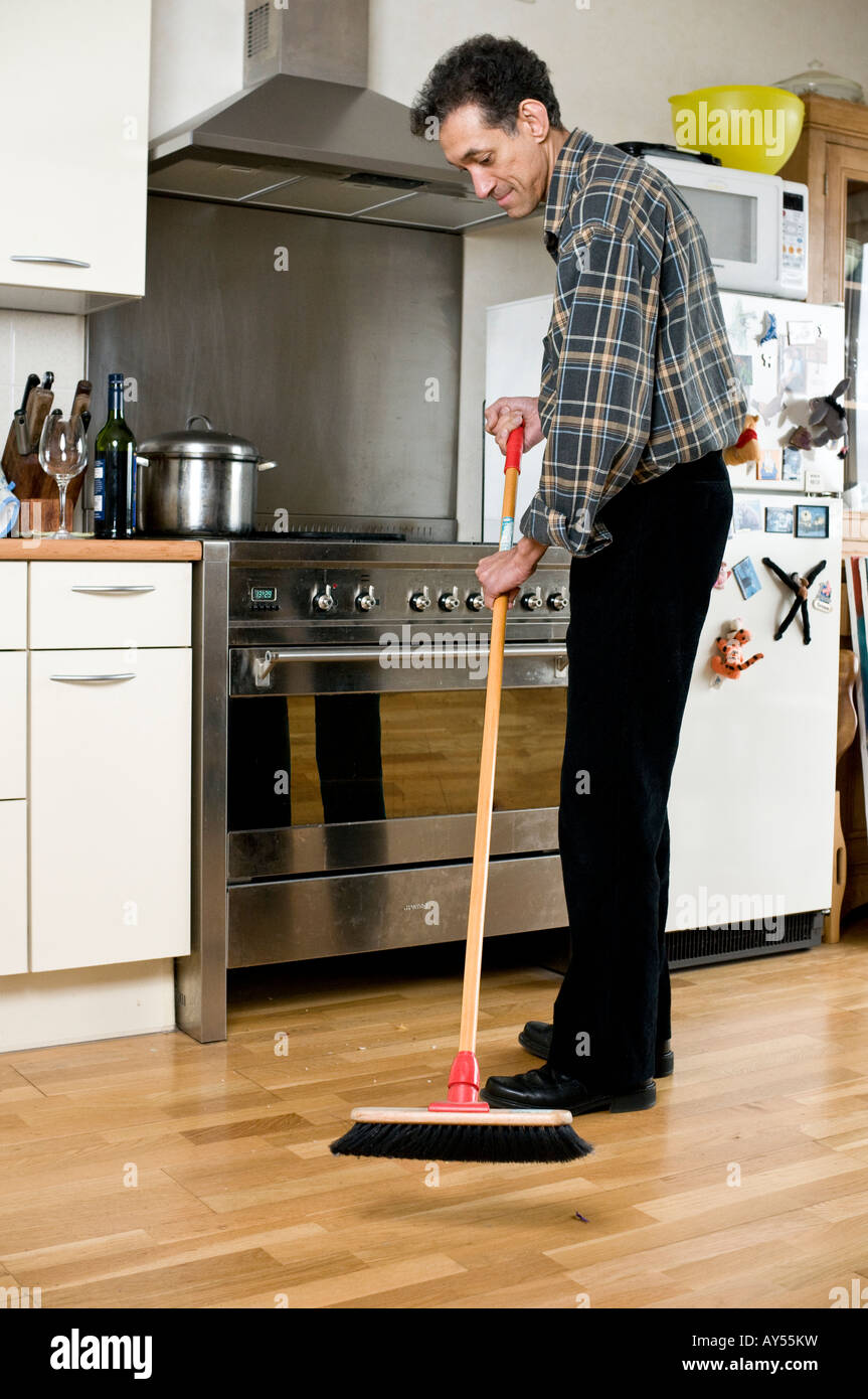 Suriname uomo la pulizia del pavimento con la scopa in cucina con fornelli  e gli armadi che mostra un frigorifero in background Foto stock - Alamy