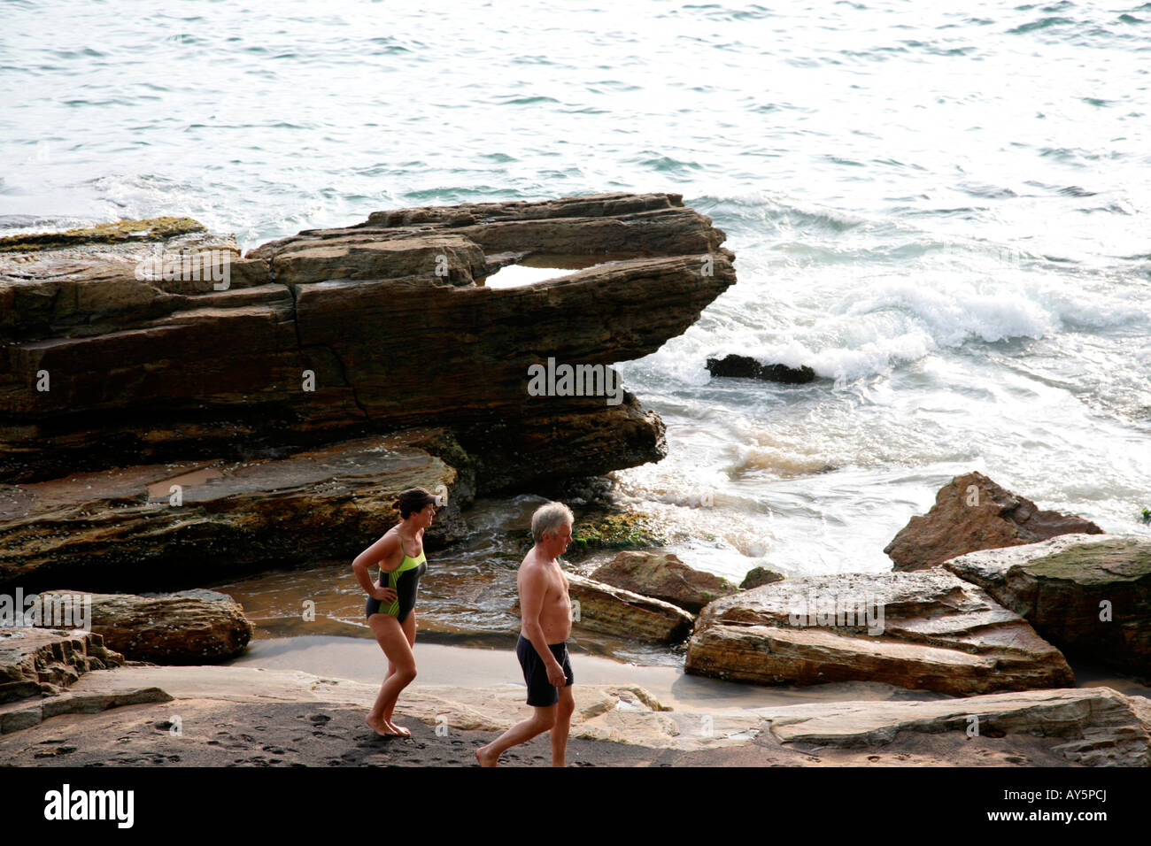 I turisti si trasferiscono nella parte rocciosa di Kovalam Beach,Kerala, India Foto Stock