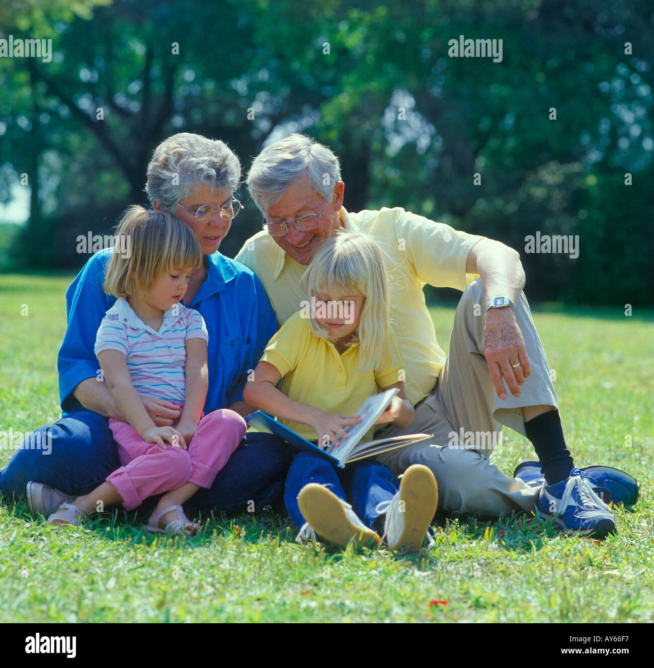Nonni con due piccole sorelle la lettura in posizione di parcheggio Foto Stock