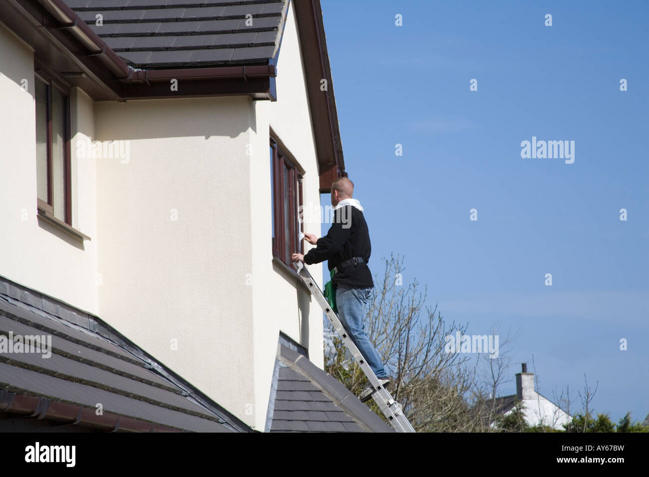 North Wales UK marzo un giovane maschio window cleaner finestre della camera da letto di una casa nazionale Foto Stock