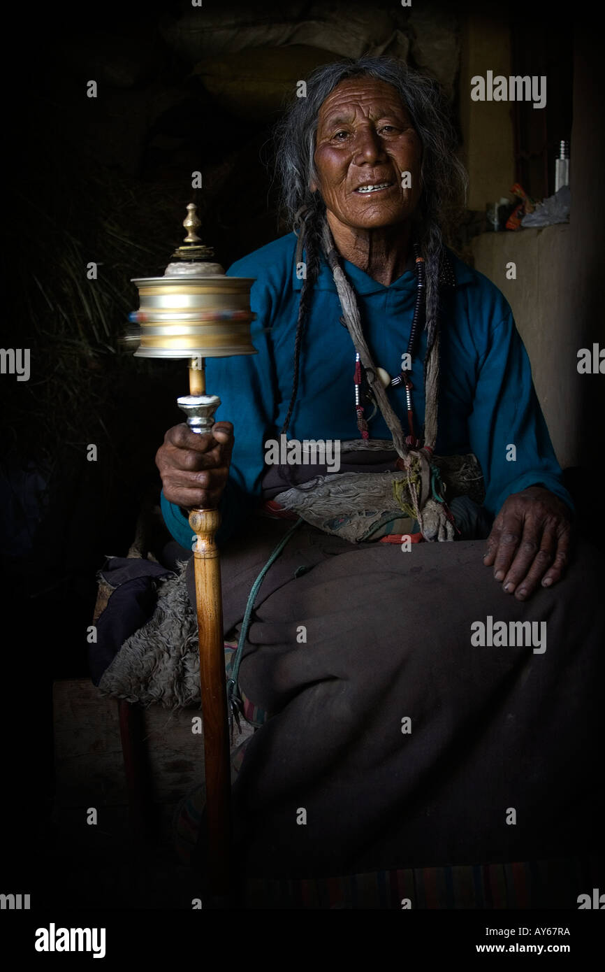 Un tibetano Donne è a sua preghiera con un pregare-ruota. Foto Stock