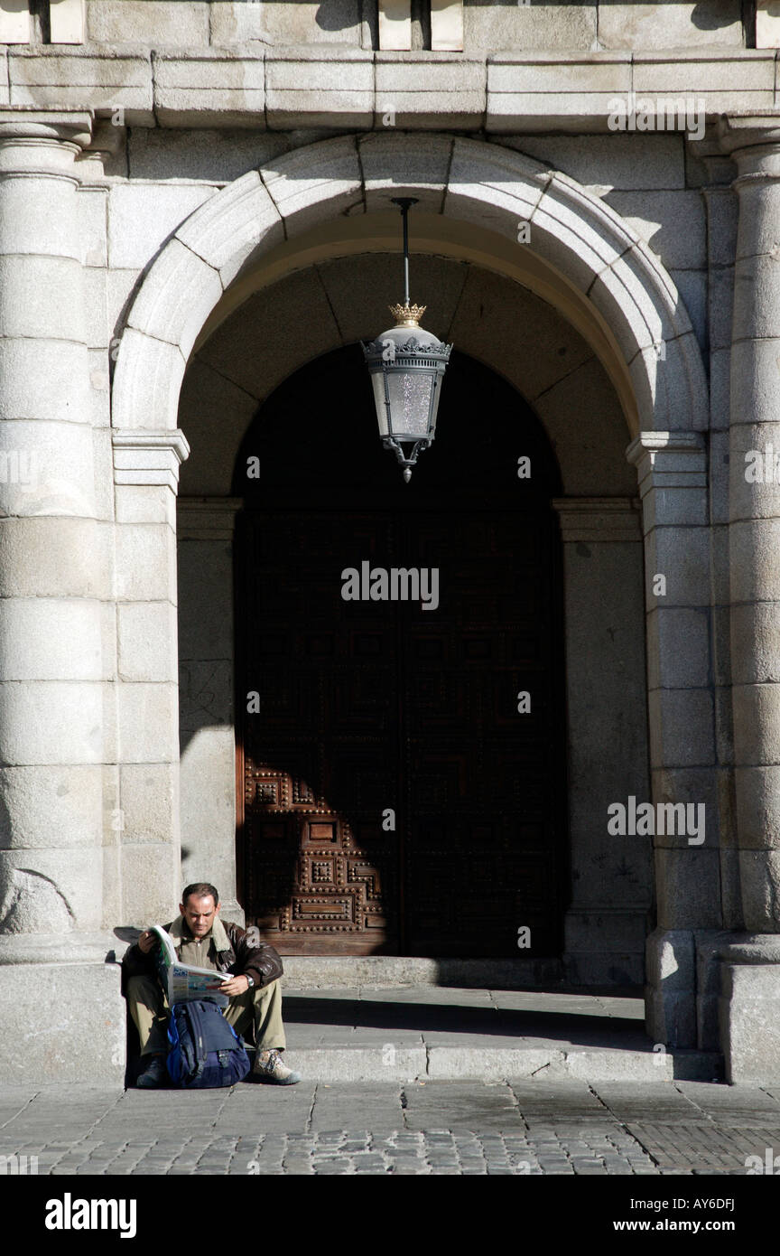 Uomo locale si rilassa con un giornale sotto gli archi di Plaza Mayor, Madrid, Spagna Foto Stock