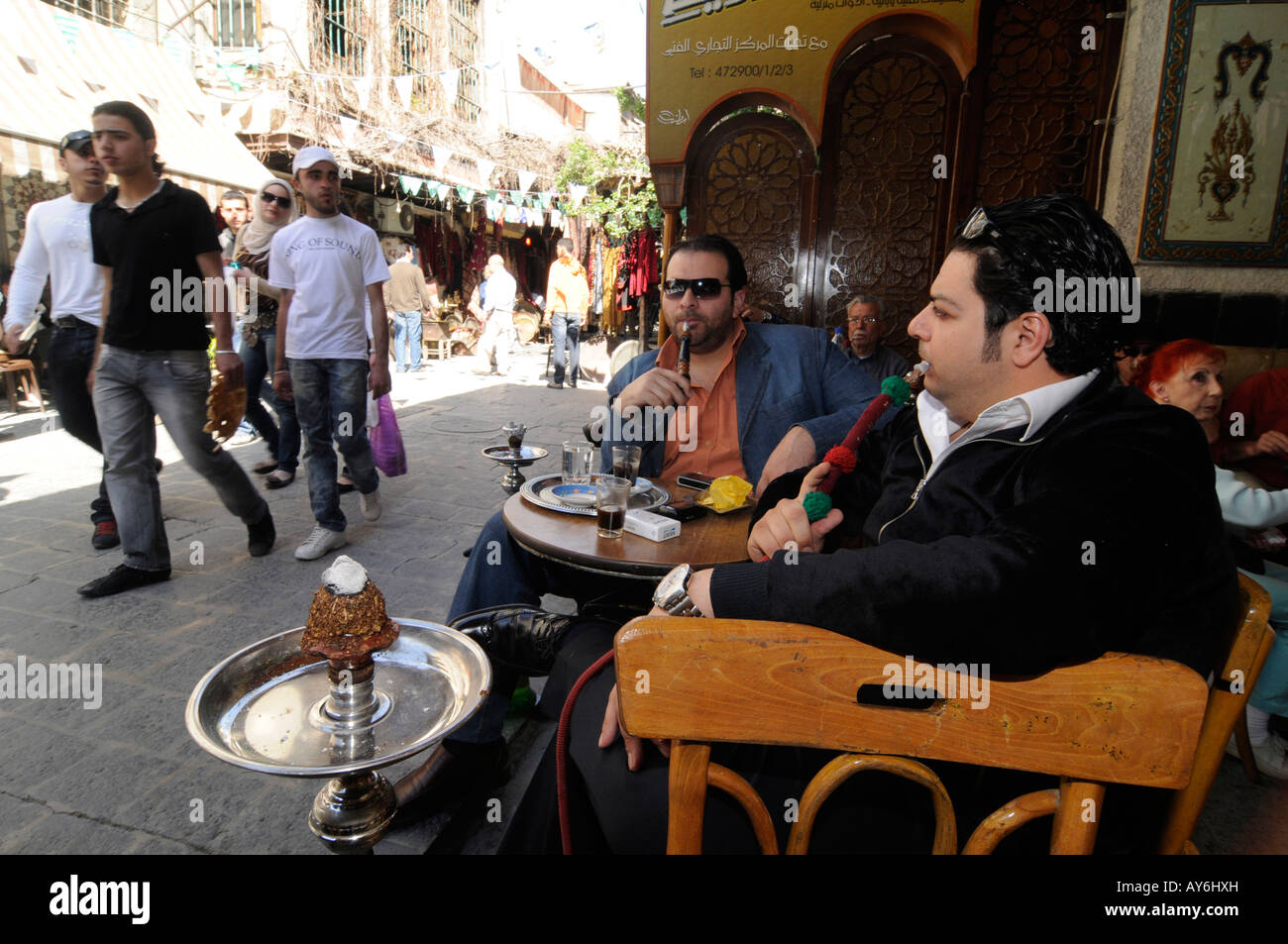 Due uomini fumatori waterpipe (narguile) senza filtro su di loro il tabacco greggio, in un coffee shop in Damasco, Siria Foto Stock