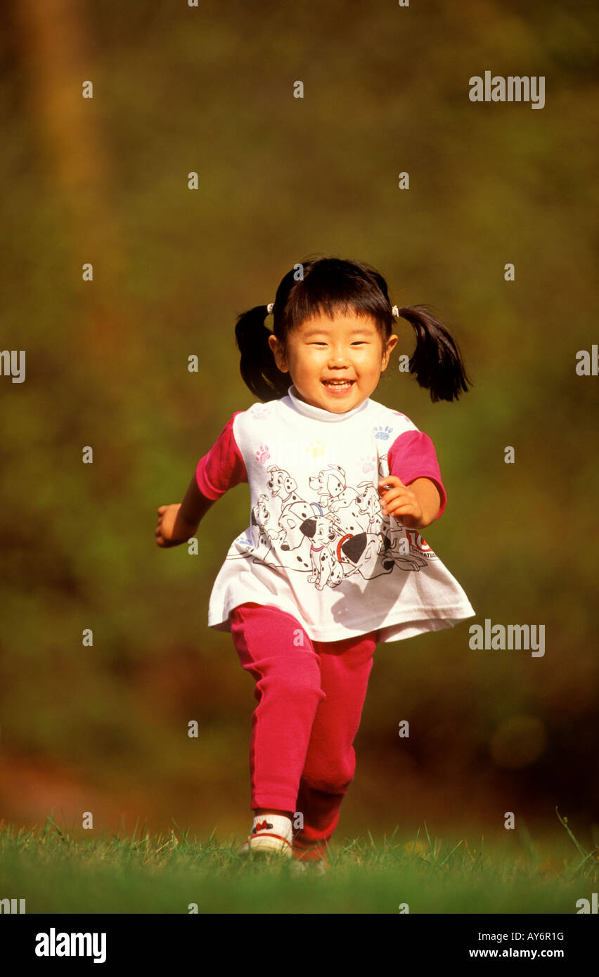 Un bambino di tre anni giapponese ragazza americana corre felicemente in un parco Foto Stock