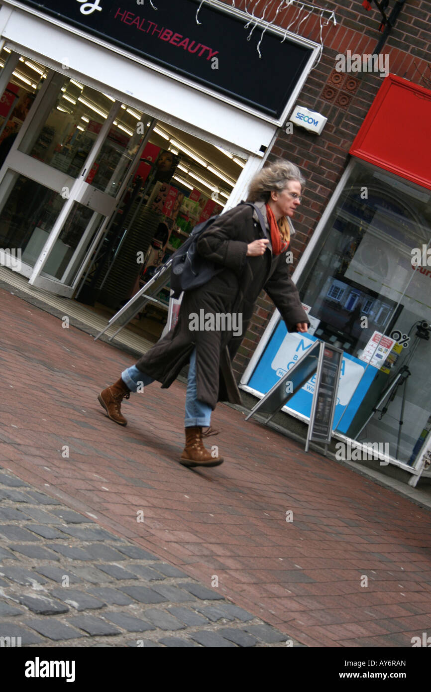 Angolo di dispari donna a piedi lungo una strada alta, shopping Foto Stock