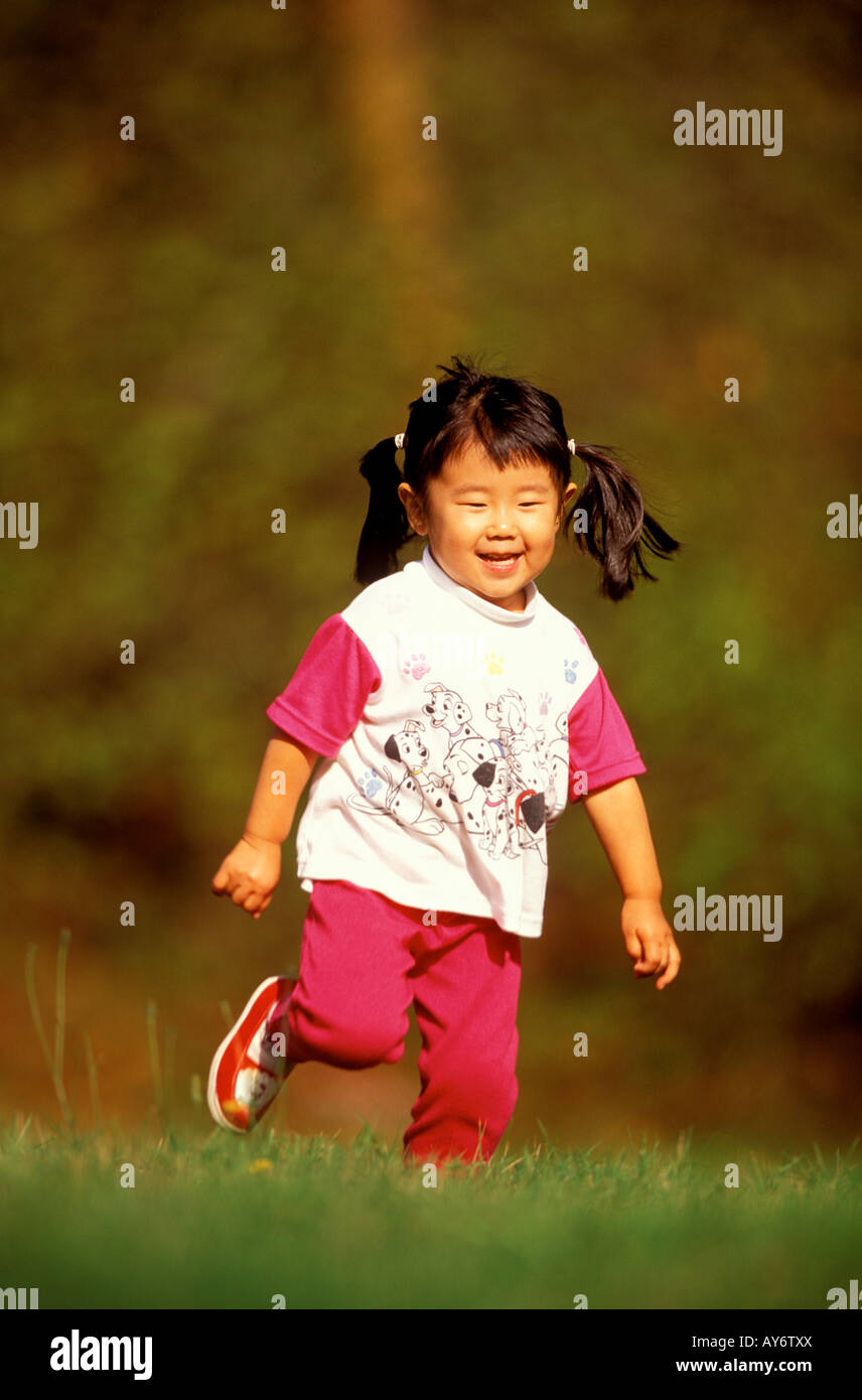 Un bambino di tre anni giapponese ragazza americana corre felicemente al sole Foto Stock