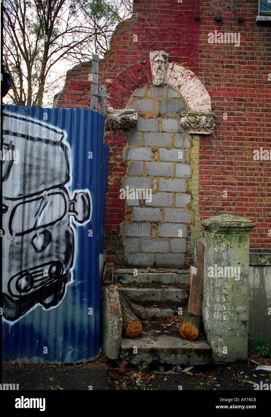 Murata porta e grafitti scherma ondulato a St Agnes posto squat nel sud di Londra. Foto Stock